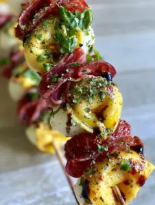 Extreme close-up of three Italian Antipasto Skewers with glistening tortellini and balsamic glaze.
