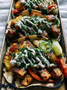 High-detail close-up of pineapple chicken tacos with blistered peppers and a lime crema drizzle on a rustic sheet pan. (pineapple chicken tacos)