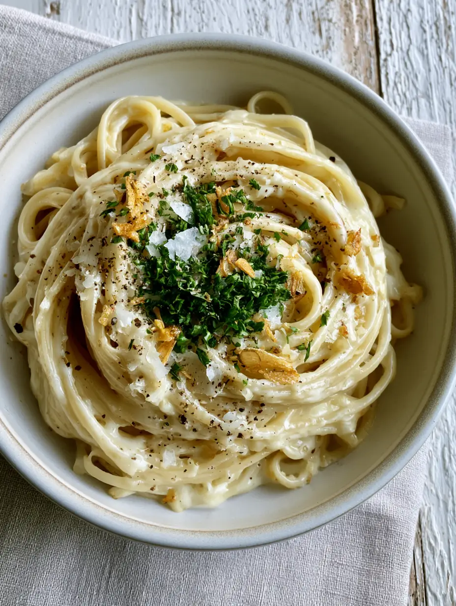 Top-down view of Creamy Garlic Pasta showing the glossy garlic butter emulsion and micro-planed cheese.