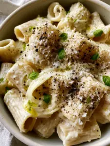 Close-up of rigatoni ridges holding a thick ivory cream sauce with microplaned parmesan dust. (Pasta recipes)